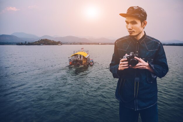 写真 川に立つ間にカメラを握る思慮深い男