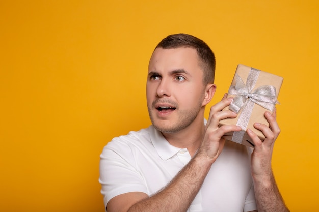 Thoughtful man holding present on yellow