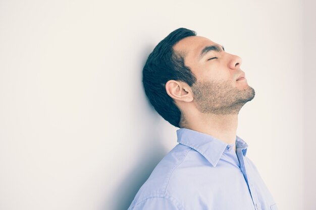 Photo thoughtful man leaning against a wall