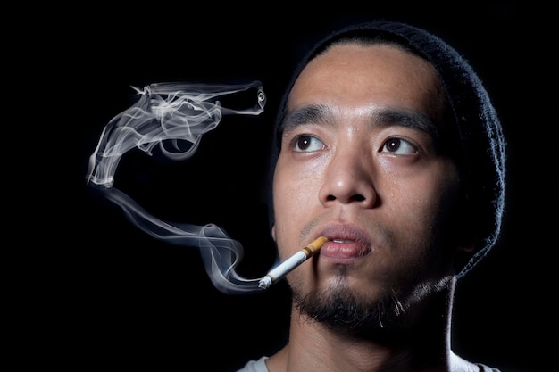 Photo thoughtful man looking away while smoking cigarette against black background