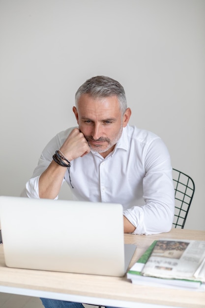 Thoughtful man looking at laptop touching face with fist