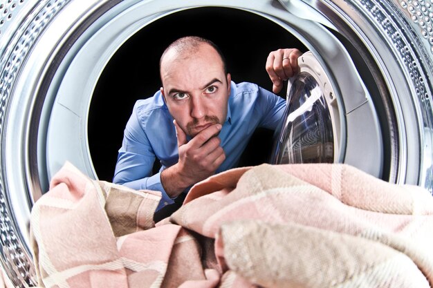 Thoughtful man looking at textile in washing machine