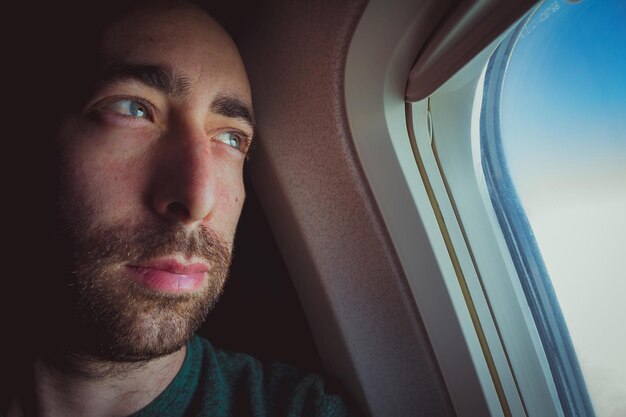 Photo thoughtful man looking through window in airplane