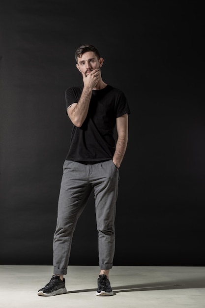 Thoughtful man posing full height on the black studio background