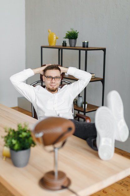 Thoughtful man sitting with feet on table in office