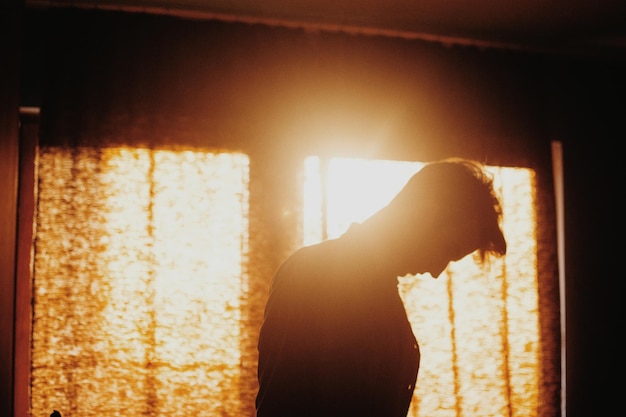 Photo thoughtful man standing against window at home