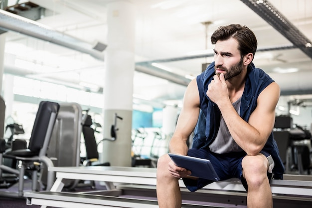 Thoughtful man using tablet at the gym