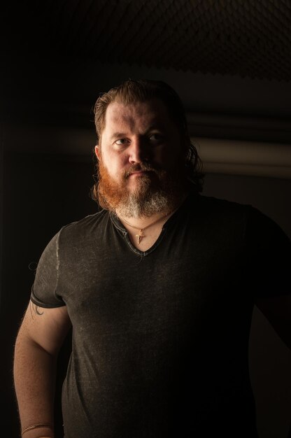 Thoughtful man with beard standing in darkroom