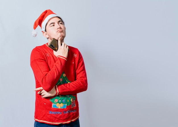 Thoughtful man with christmas hat holding cell phone young man
in christmas clothes thoughtful with cell phone isolated handsome
man in christmas clothes thoughtful holding cell phone