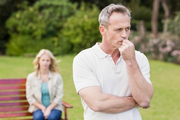 Thoughtful man with girlfriend sitting behind in the garden