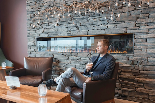 Thoughtful man with wineglass sitting in chair at luxury hotel