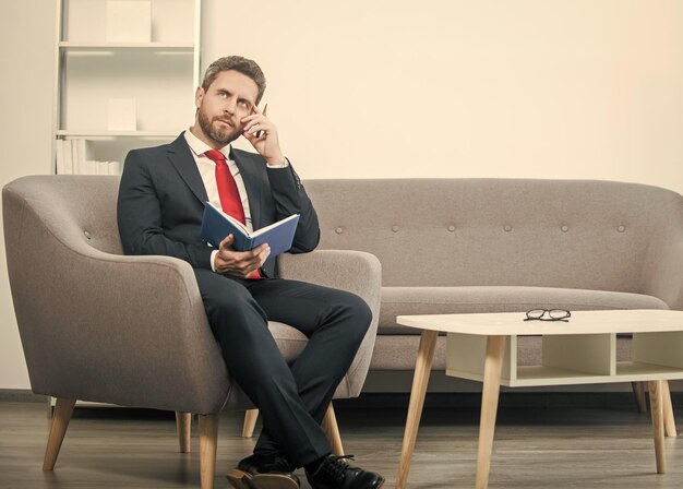 Thoughtful mature businessman in suit sit in office with planner