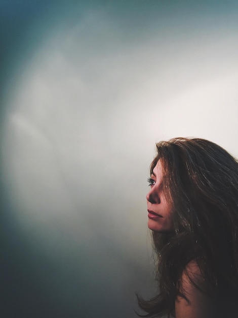 thoughtful mature woman looking away against wall