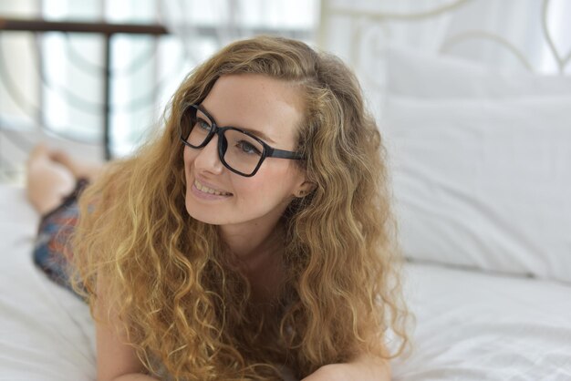 Thoughtful mid adult woman lying on bed at home