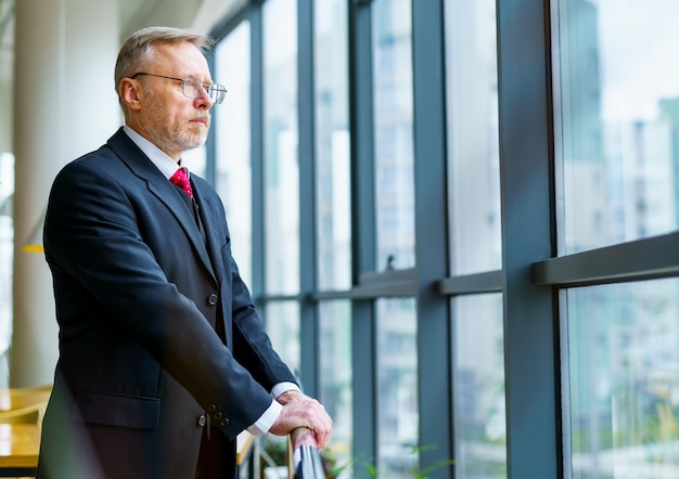 Thoughtful middle aged businessman in suit looking at window Having rest in modern office Business concept