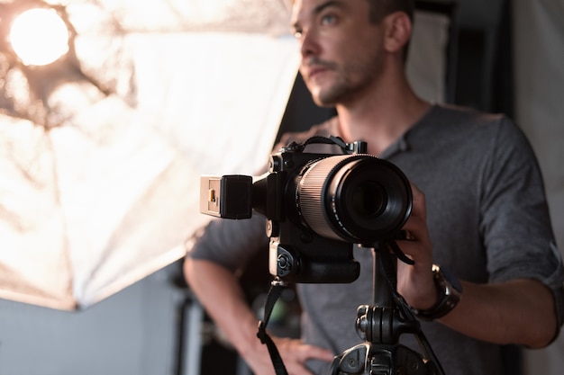 A thoughtful photographer with a camera on the background lighting equipment