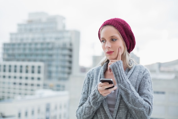 Thoughtful pretty blonde text messaging outdoors