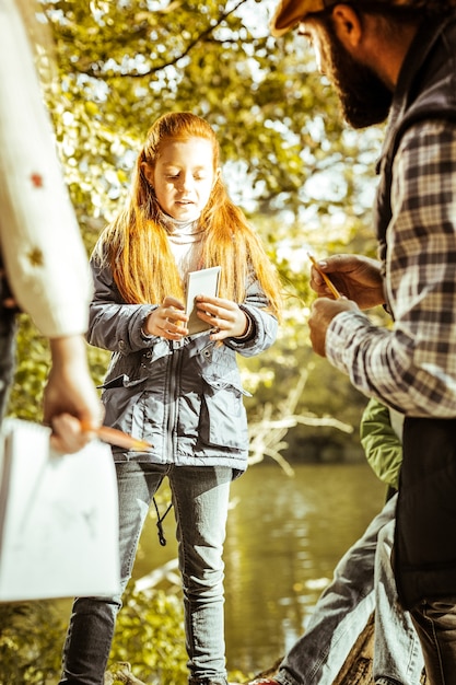 A thoughtful red haired girl during a lesson in forest on a good day