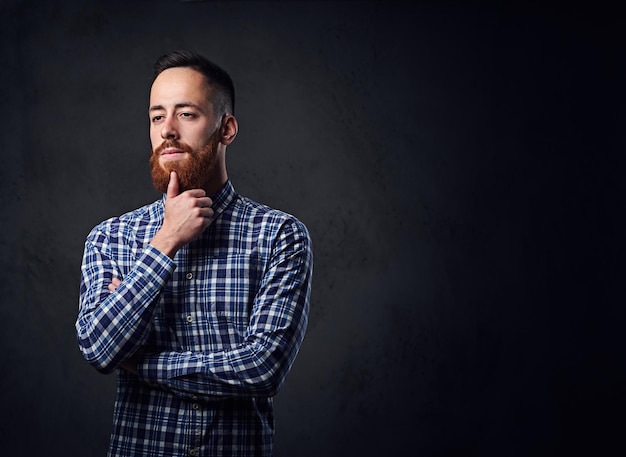 Thoughtful redhead bearded hipster male with crossed arms, dressed in a blue fleece shirt.