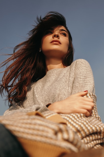 Thoughtful sad woman in warm sweater with flying hair