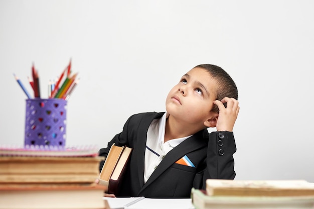 Thoughtful schoolboy scratching head and thinking on new ideas
