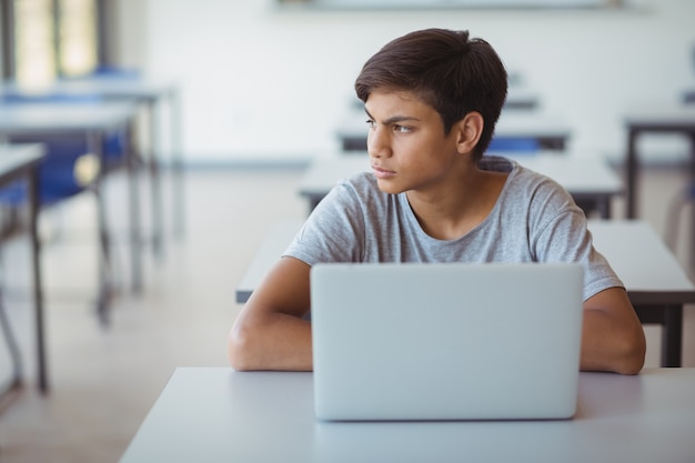 Scolaro premuroso che si siede con il computer portatile in aula