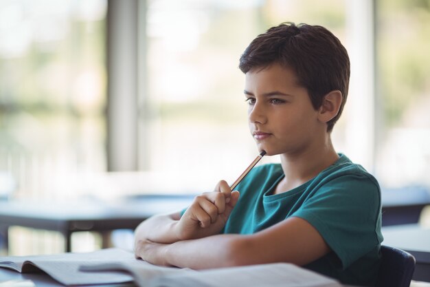 Thoughtful schoolboy studying in classroom