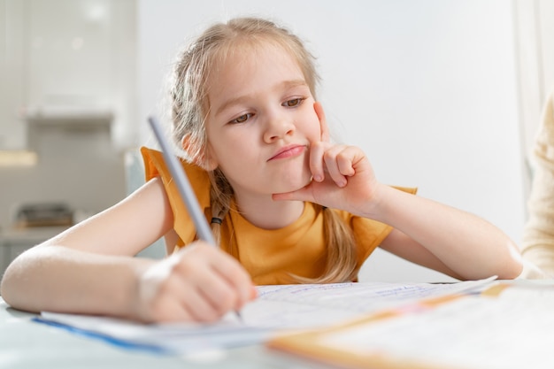 thoughtful schoolgirl does homework. complexities of correct and beautiful handwriting.