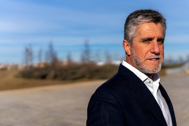 Photo thoughtful senior man looking at camera on street