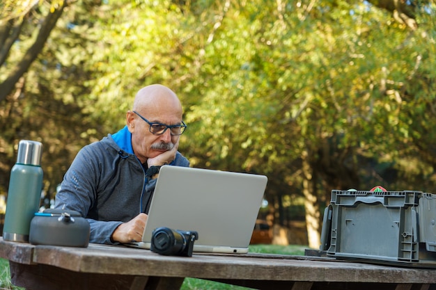 Thoughtful Senior Man Using Computer in Nature