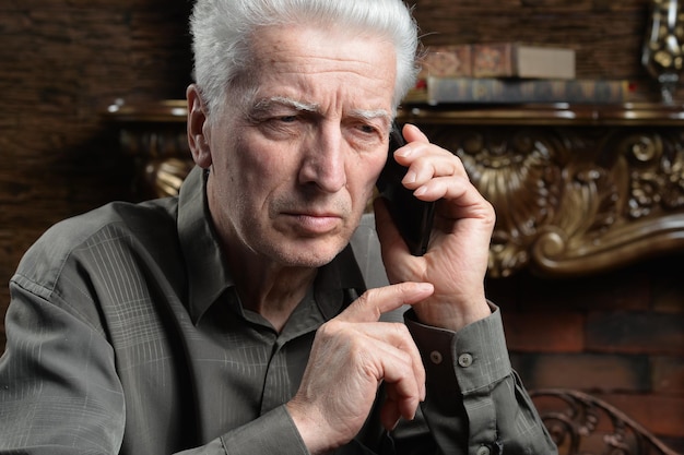 Thoughtful senior man with smartphone