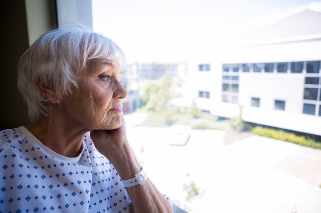 Foto paziente senior premuroso che osserva attraverso la finestra