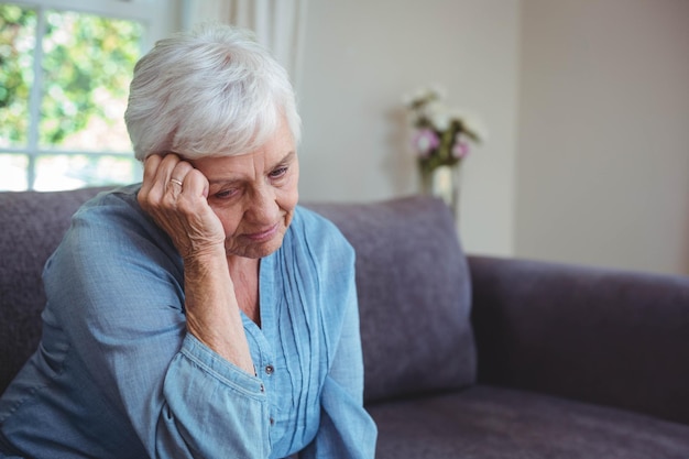 thoughtful senior woman sitting on sofa