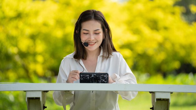 Thoughtful smile Happy woman videocalling online or meeting online working with a laptop in a park