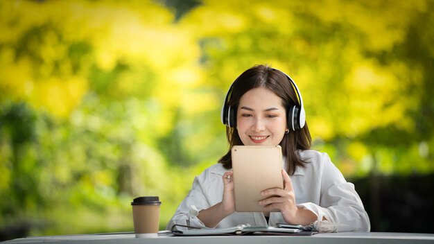 Thoughtful smile Happy woman videocalling online or meeting online working with a tablet in a park