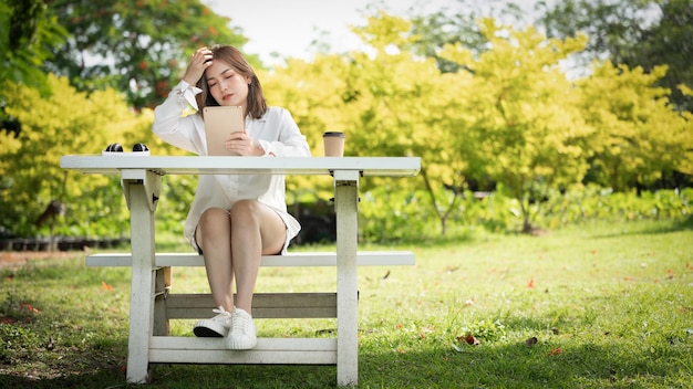 사진 스마트 디지털 태블릿을 사용하여 공원에서 사려 깊은 미소 여자 젊은 매력적인 비즈니스의 초상화