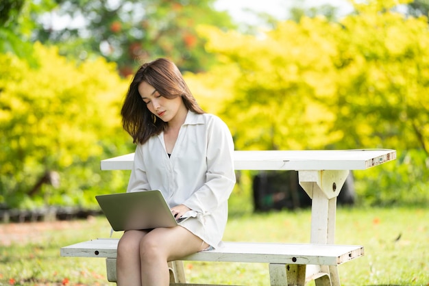 スマートデジタルタブレットを使用して公園で思いやりのある笑顔の女性若い魅力的なビジネスの肖像画