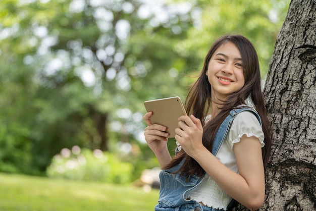 スマートデジタルタブレットを使用して公園で思いやりのある笑顔の女性若い魅力的なビジネスの肖像画