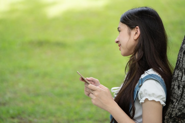 Thoughtful smile woman in park using smart digital tablet Portrait of a young charming business