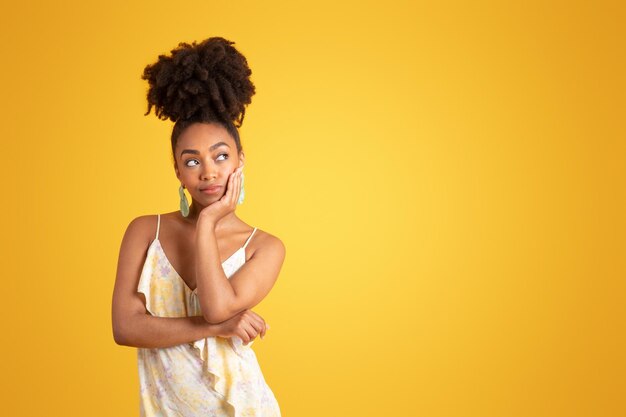 Thoughtful smiling millennial african american lady in dress thinking looking at empty space