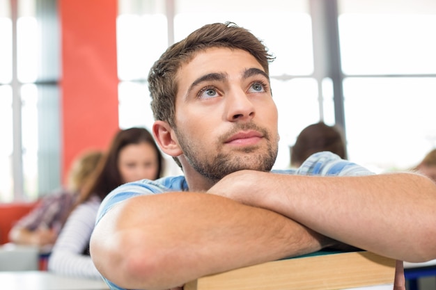 Thoughtful student with books in classroom