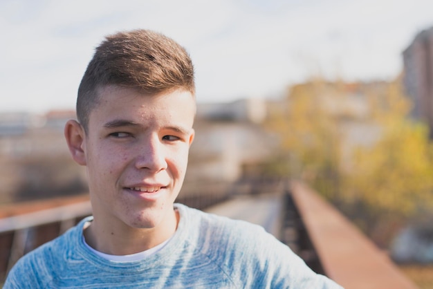 Thoughtful teenage boy standing on footbridge in city