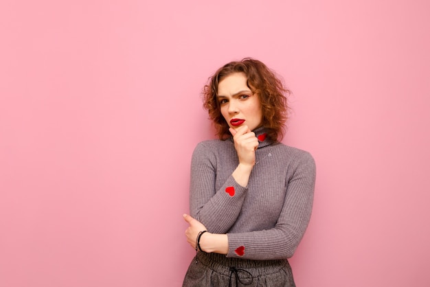 Thoughtful teenager girl with curly red hair and in a gray sweater