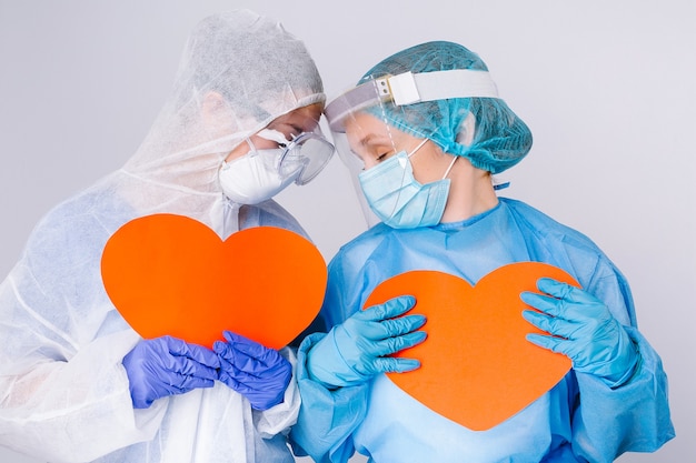 Thoughtful, tired doctors in uniform with big red hearts in their hands. valentines day, charity, giving back, pandemic