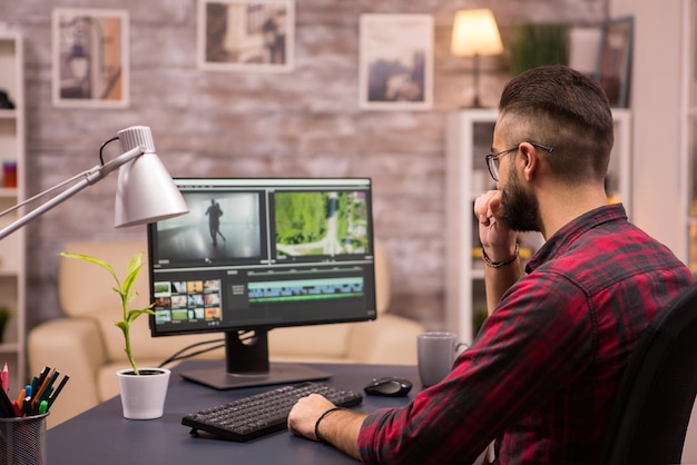 Photo thoughtful videographer while working in a movie on computer from home.