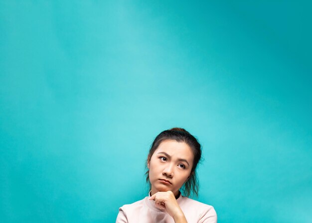 Thoughtful woman against turquoise background