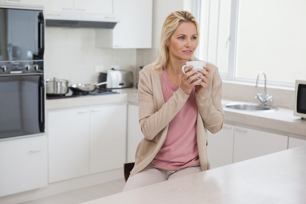 キッチンでコーヒーを飲む思いやりのある女性