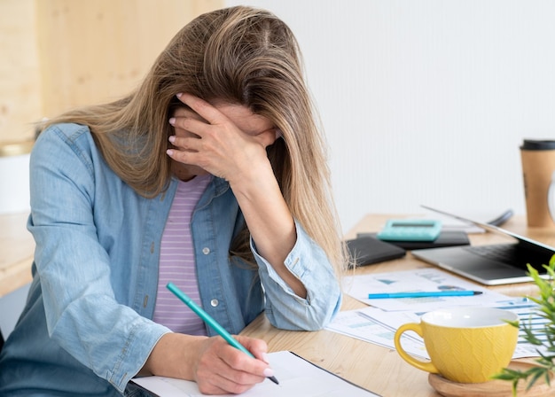 A thoughtful woman drinking a lot of coffee while doing creative work