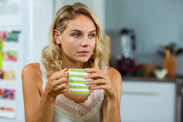 Thoughtful woman having coffee at home