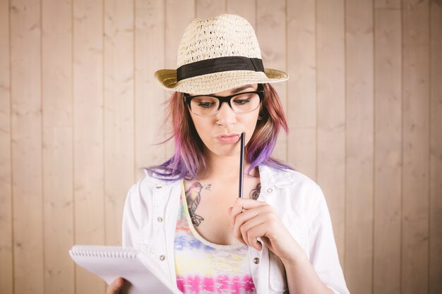 Thoughtful woman holding notepad and pen